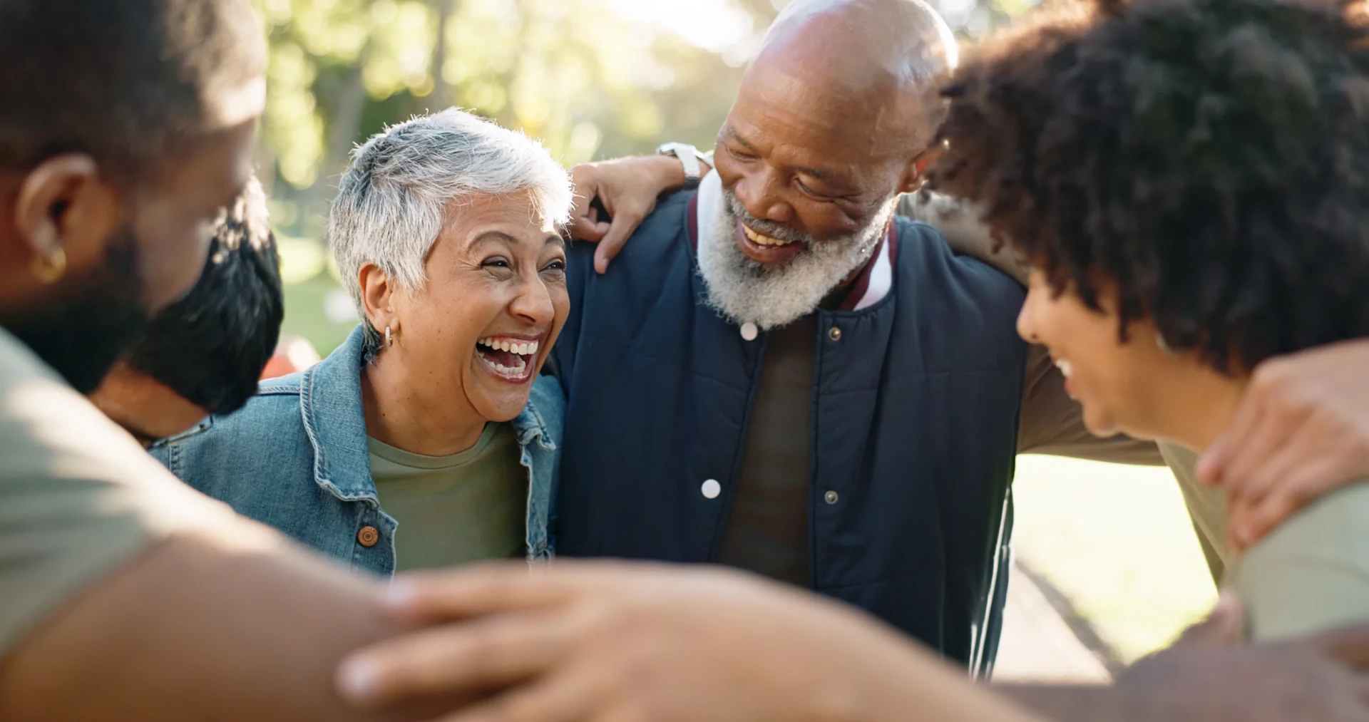 A group of older adults and caregivers laughing together outdoors during an INSPIRE community connection